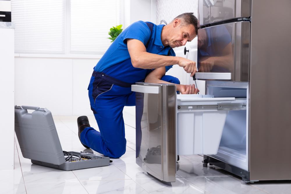Technician repairing a refrigerator in a customer's kitchen