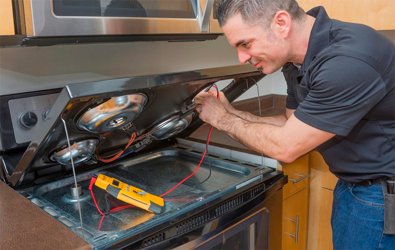 Technician testing a stove with a multimeter